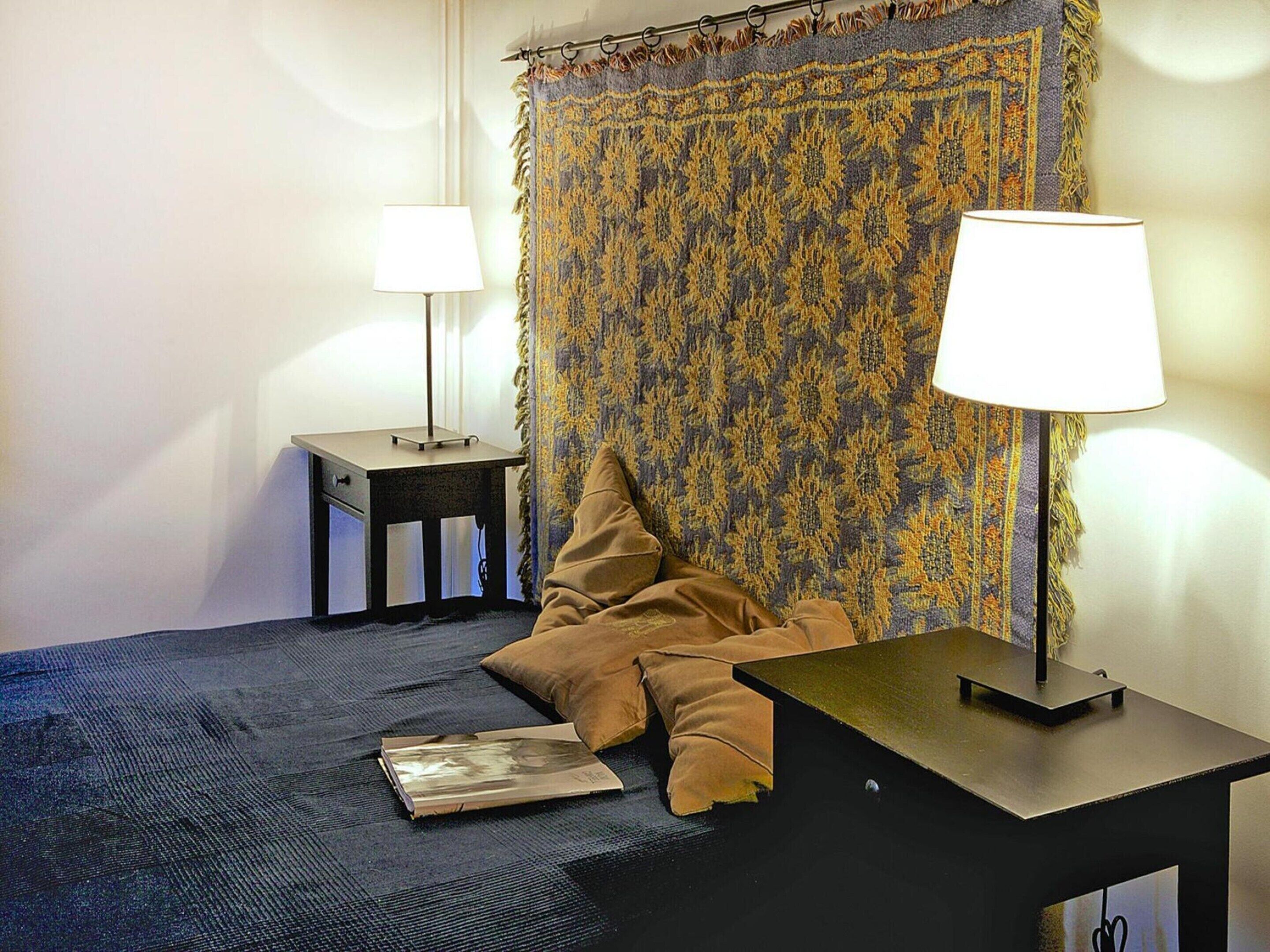 Ett sovrum med en säng, två sängbord, en lampa, en kudde och en bok.