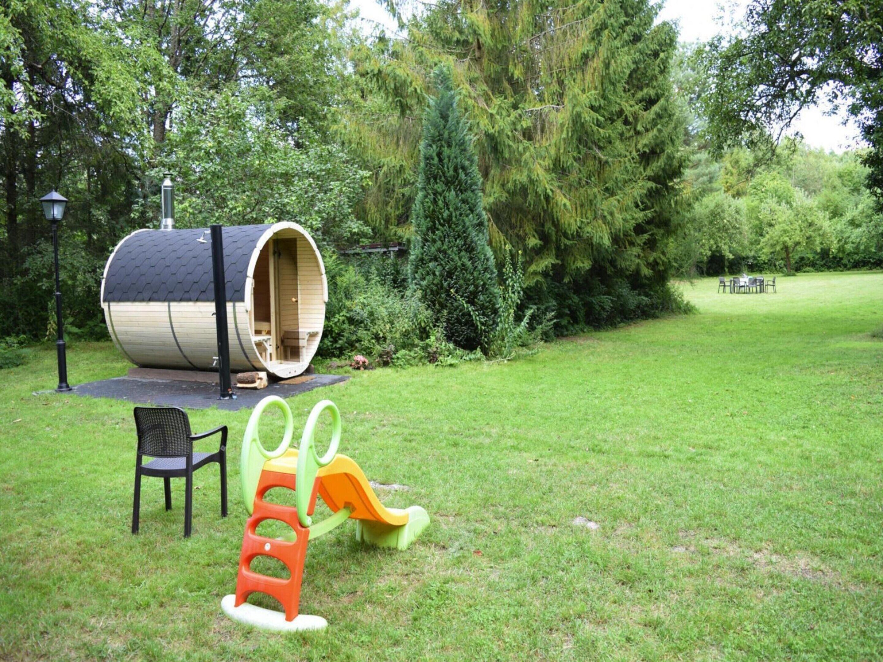 A large cylindrical structure with a door, a small outdoor seating area with a table and chairs, and a children's play structure with slides.
