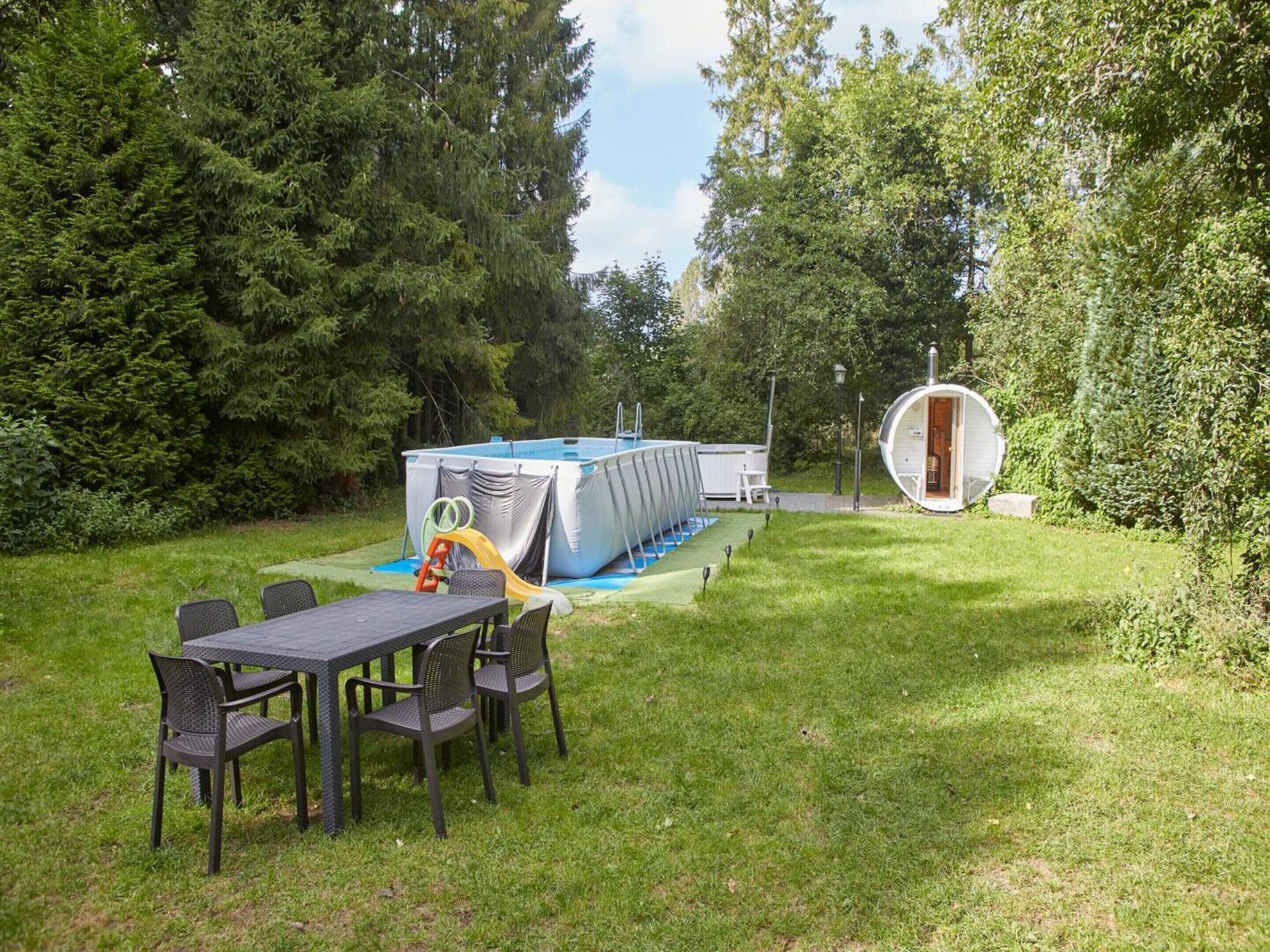 A pool area with a slide, a table with chairs, and a circular structure.