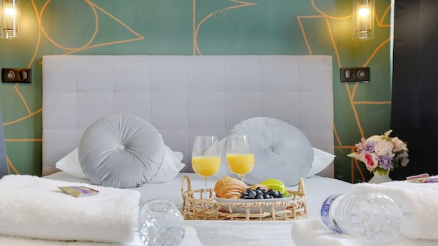 A neatly made bed with a headboard, two pillows, a tray with croissants, blueberries, and glasses of orange juice. - Serene Apartment for 6p Near the Marais (Paris)