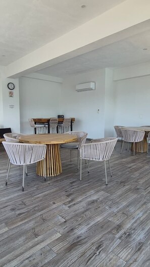 A spacious room with a large wooden table surrounded by white chairs, a clock on the wall, and an air conditioning unit. - Relax, Unwind and Experience Vallarta (Puerto Vallarta)