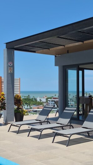 Una terrassa al terrat amb seients relaxants, una pérgola i vista a l'oceà.