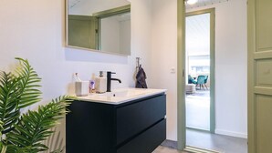 A modern bathroom with a black vanity, white sink, and a large mirror. - 4 Star Holiday Home in Faxe Ladeplads (Faxe Ladeplads)