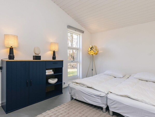 A bedroom with a bed, a wardrobe, and a floor lamp. - 4 Star Holiday Home in Faxe Ladeplads (Faxe Ladeplads)