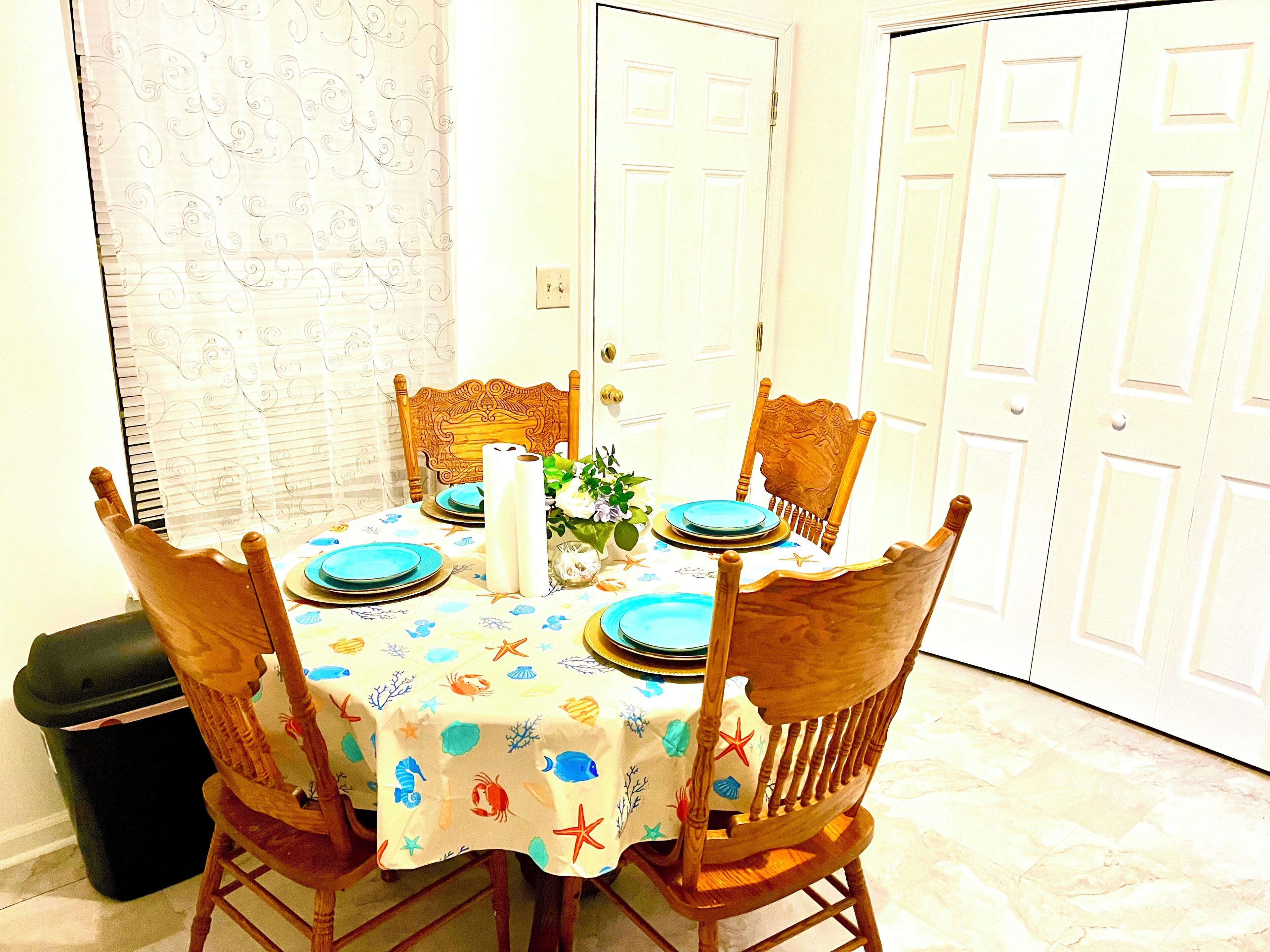 Una mesa de comedor con mantel de temática náutica, rodeada de sillas de madera.