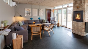 A modern living room with a sectional sofa, a small wooden table, and a fireplace. - 5 Star Holiday Home in Vestervig (Vestervig)