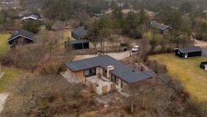 A residential area with multiple houses, a large open yard, and a prominent house with a modern design and large windows. - 5 Star Holiday Home in Vestervig (Vestervig)
