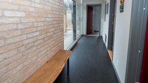 A hallway with a brick wall, a bench, and a door leading to a bathroom. - 5 Star Holiday Home in Vestervig (Vestervig)