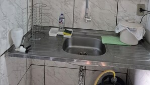 Et køkken med vask, vanddispenser og opvaskestativ.