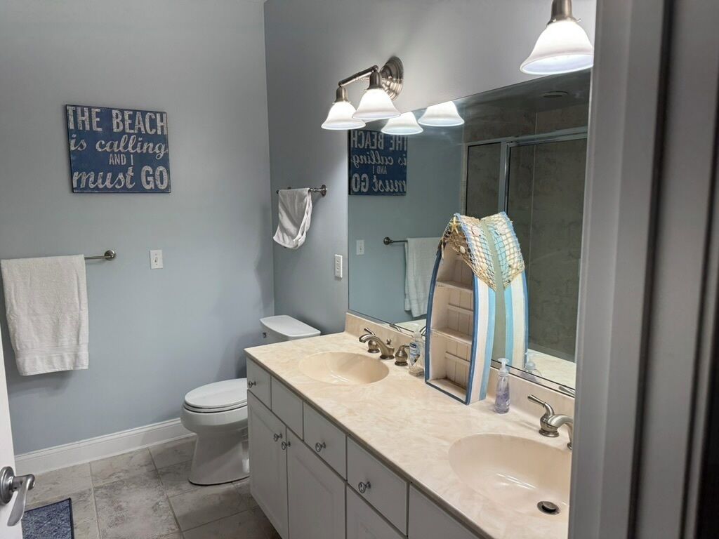 A bathroom with two sinks, a toilet, a towel rack, and a mirror.