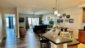 Una cucina moderna con isola centrale, sgabelli da bar e zona pranzo con divano e sedie.