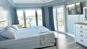 Una camera da letto con un letto, un ventilatore a soffitto, una televisione e vista sull'esterno.