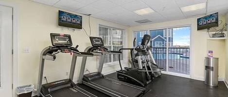 A gym with treadmills, ellipticals, and a TV screen displaying 'LOVE'.