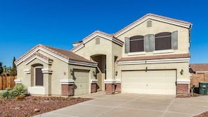 A two-story house with a garage, a covered driveway, and a landscaped front yard.