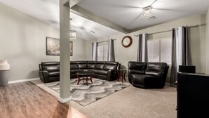 A spacious living room with a sectional sofa, a leather armchair, and a coffee table.