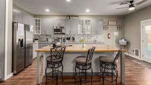 A modern kitchen with a central island, stainless steel appliances, and two bar stools.
