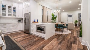 Una cucina moderna con mobili bianchi, un'isola centrale e una zona pranzo con un tavolo rotondo e sedie.