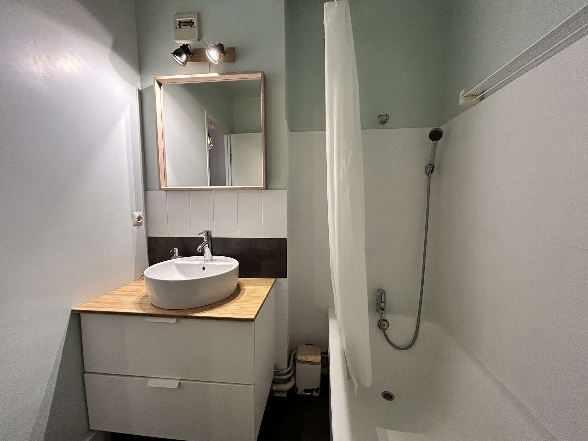 A bathroom with a sink, mirror, and shower.