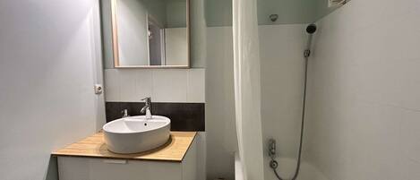 A bathroom with a sink, mirror, and shower.
