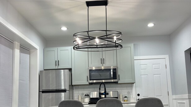 Een moderne keuken met een centraal eiland, roestvrijstalen apparatuur en een bijzondere hanglamp.