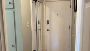 A narrow hallway with wooden flooring, white walls, and a closed door at the end. - Cute 1-bedroom condo in Denver's Cap Hill neighborhood (Denver)