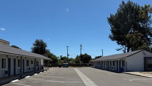 A motel with a parking lot, a covered walkway, and a row of rooms. - Angel Motel near Anaheim  (Orange)