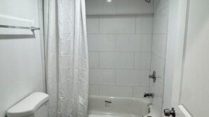 A bathroom with a toilet, shower, and bathtub. - Angel Motel near Anaheim  (Orange)