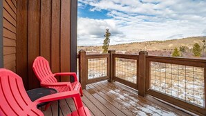 A wooden deck with red chairs and a view of a hilly landscape. - Meadow View Townhome with Hot Tub (Fraser)