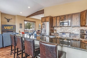 A modern kitchen with granite countertops, stainless steel appliances, and wooden cabinets. - Meadow View Townhome with Hot Tub (Fraser)