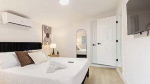 Une chambre d’hôtel équipée d’un lit, d’une table de chevet, d’une lampe et d’un appareil de climatisation.