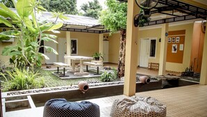 Un espacio tranquilo al aire libre con mesa y bancos, rodeado de exuberante vegetación y una pequeña fuente.