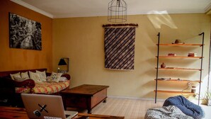 Una sala de estar acogedora con una cama, una mesa de centro de madera, una computadora portátil y un sillón de peluche.