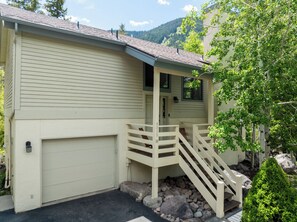 A two-story house with a covered porch and a garage. - Spruce Park H - Cozy East Vail Home with Private Hot Tub + Easy Village Access (Vail)