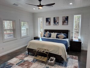 Quarto com cama, mesa de cabeceira, abajur e janela.
