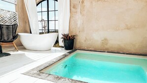 A small outdoor pool area with a white bathtub, a chair, and a potted plant. - Romantic Private Pool Suite with outdoor tub Rincon, close to beaches (Rincon)