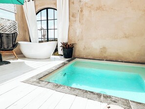 Ein kleiner Außenpoolbereich mit einer weißen Badewanne, einem Stuhl und einem Blumentopf.