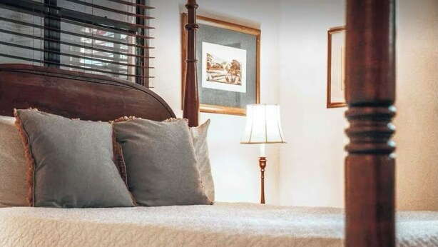 A bedroom with a wooden headboard, two pillows, a bedside lamp, and framed pictures on the wall. - Romantic Private Pool Suite with outdoor tub Rincon, close to beaches (Rincon)