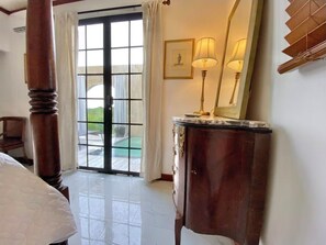 Ein Hotelzimmer mit großem Fenster, einer Holzsäule, einem Marmorplatten-Kommode und einem gerahmten Bild an der Wand.