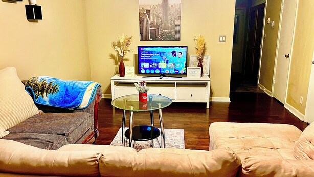 A living room with a sofa, a coffee table, a TV, and a cityscape poster on the wall.