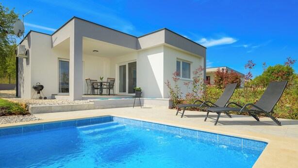A modern house with a swimming pool, outdoor furniture, and a satellite dish.