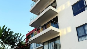 Un immeuble à plusieurs étages doté de balcons, de grandes fenêtres et d’un escalier menant à l’entrée.