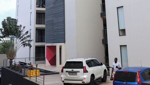 Un bâtiment moderne à la façade blanche, doté de nombreux balcons et présentant un élément de design géométrique.
