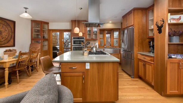 A spacious kitchen with wooden cabinets, a central island, and a dining area with a table and chairs.