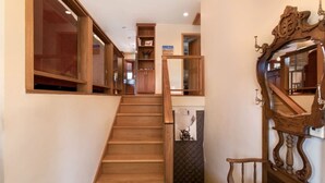 A wooden staircase leading to a lower level with a dark quilted wall and a wooden chair.