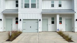 En tvåvåningsbyggnad med en symmetrisk fasad, som har en central garageport och två sidointräden.