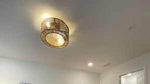 Ett sovrum med en säng, ett nattduksbord, en vägglampa och en taklampa.