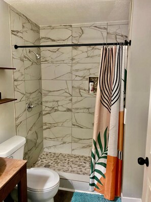 Une salle de bain équipée de toilettes, d’une douche et de carreaux de marbre.
