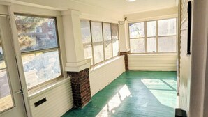 Ein Zimmer mit großen Fenstern, einem grünen Boden und weißen Wänden.