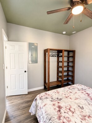 Une chambre à coucher avec un lit, une armoire en bois, un ventilateur de plafond et une porte blanche.
