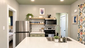 Une cuisine moderne dotée d’un îlot central, d’appareils électroménagers en acier inoxydable et donnant sur l’espace de vie adjacent.